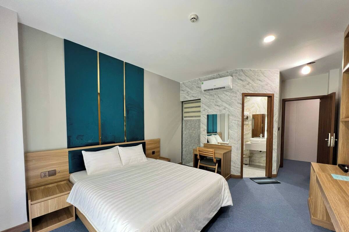 Una habitación de hotel con una cama grande, un escritorio con una silla, un espejo y un armario.