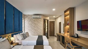 Quarto de hotel com cama, mesa de cabeceira, abajur e escrivaninha com cadeira.