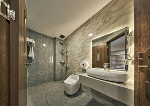 Un baño moderno con una bañera independiente, un espejo grande y una pared de mármol.