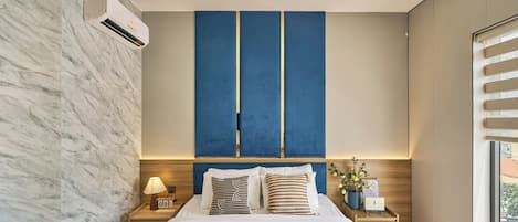 A modern bedroom with a bed, nightstands, a wall-mounted air conditioner, and a window with blinds.