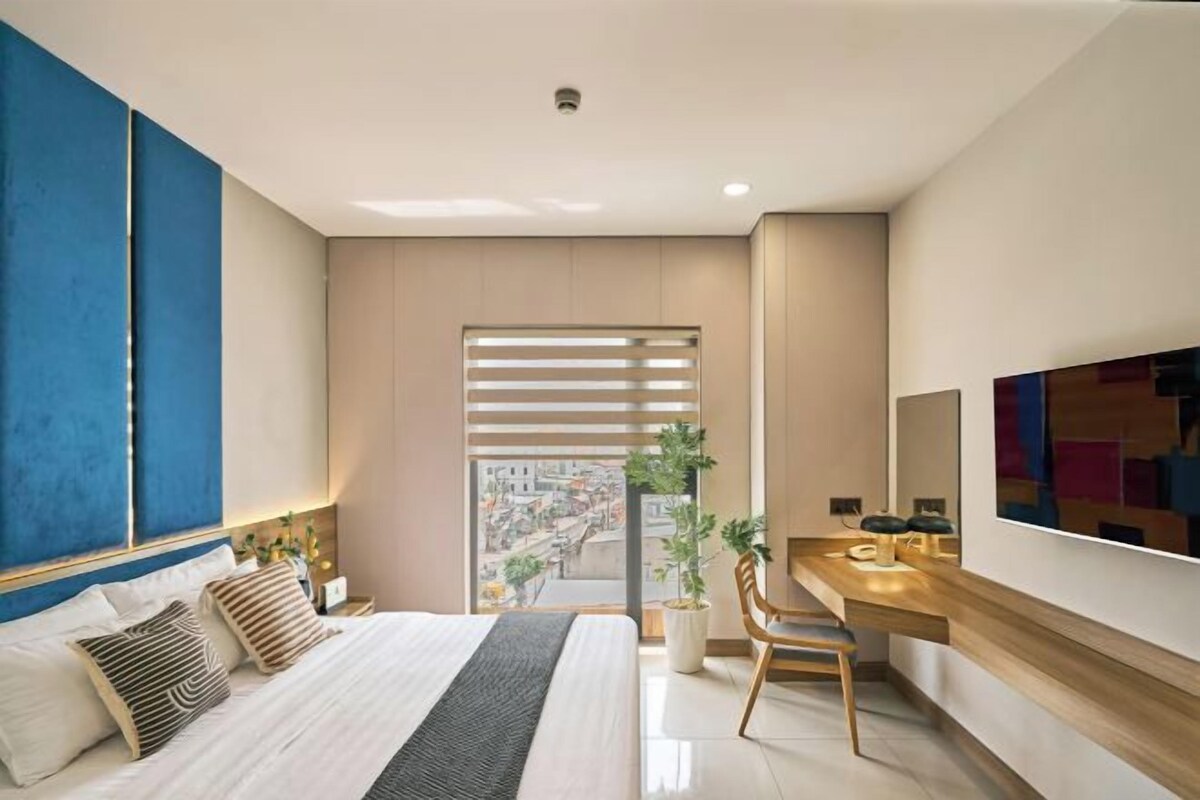 Un dormitorio moderno con una cama grande, un escritorio y vista a la ciudad.