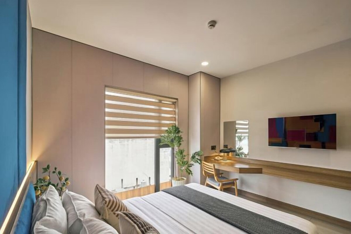 Un dormitorio moderno con cama, mesita de noche y un ventanal con persianas.