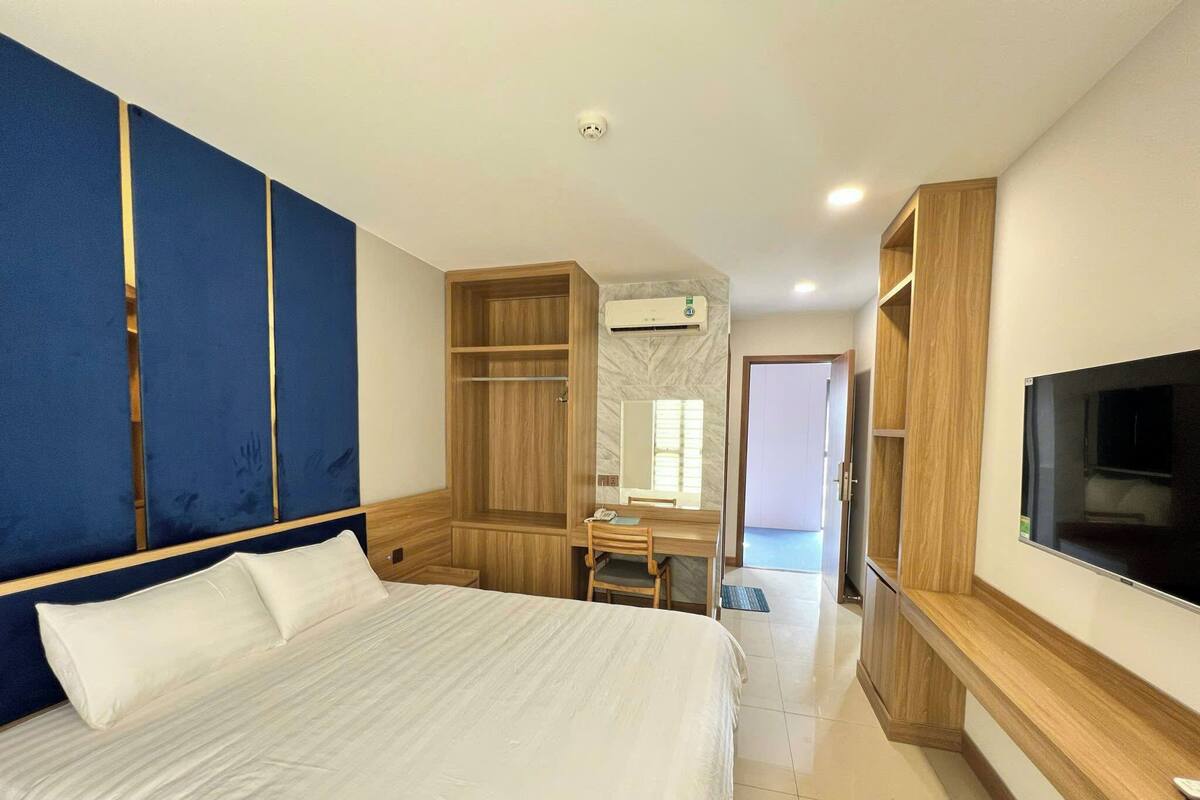 Un dormitorio con una cama grande, un escritorio, un armario y un televisor.