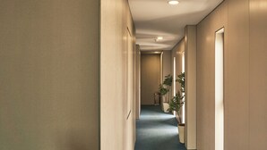 A hotel hallway with a carpeted floor, recessed lighting, and potted plants. - Tran Long District 12 (Ho Chi Minh City)