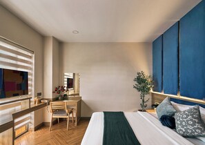 Een hotelkamer met een bed, een bureau, een stoel, een spiegel en een plant.