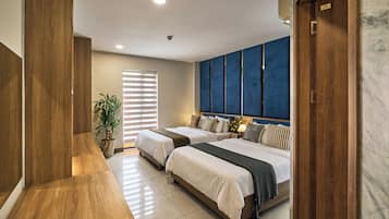 Habitación de hotel con dos camas, un ventanal con persianas, una planta en maceta y una pared de acento azul.