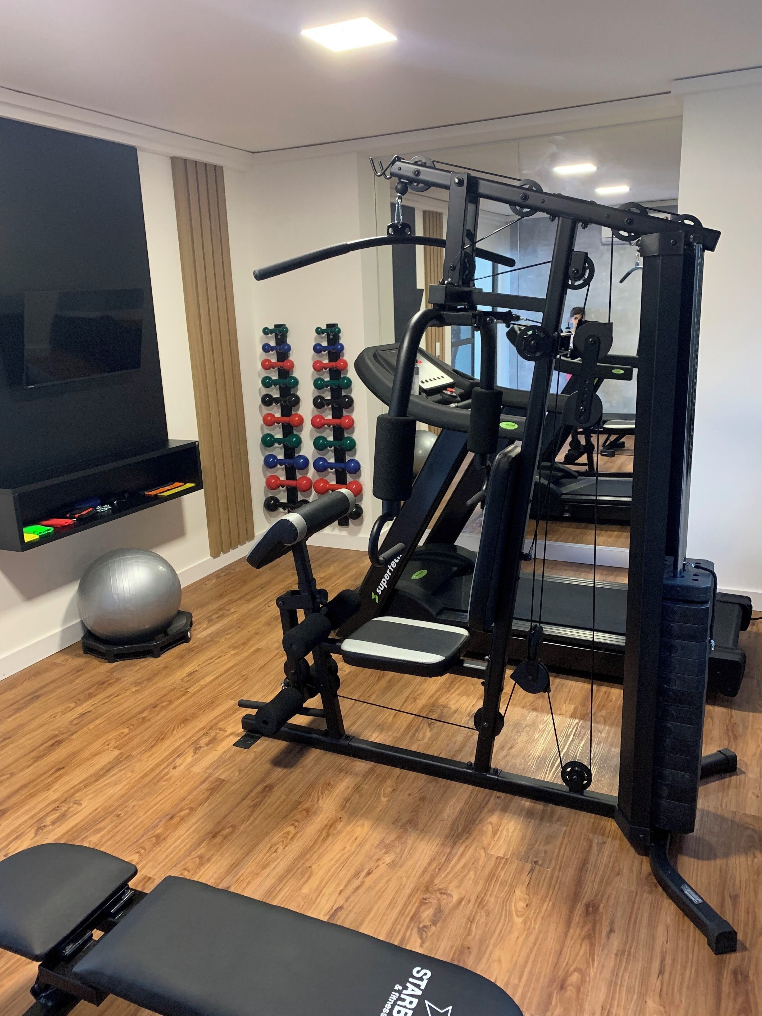 A home gym with a treadmill, weight machine, and exercise ball.