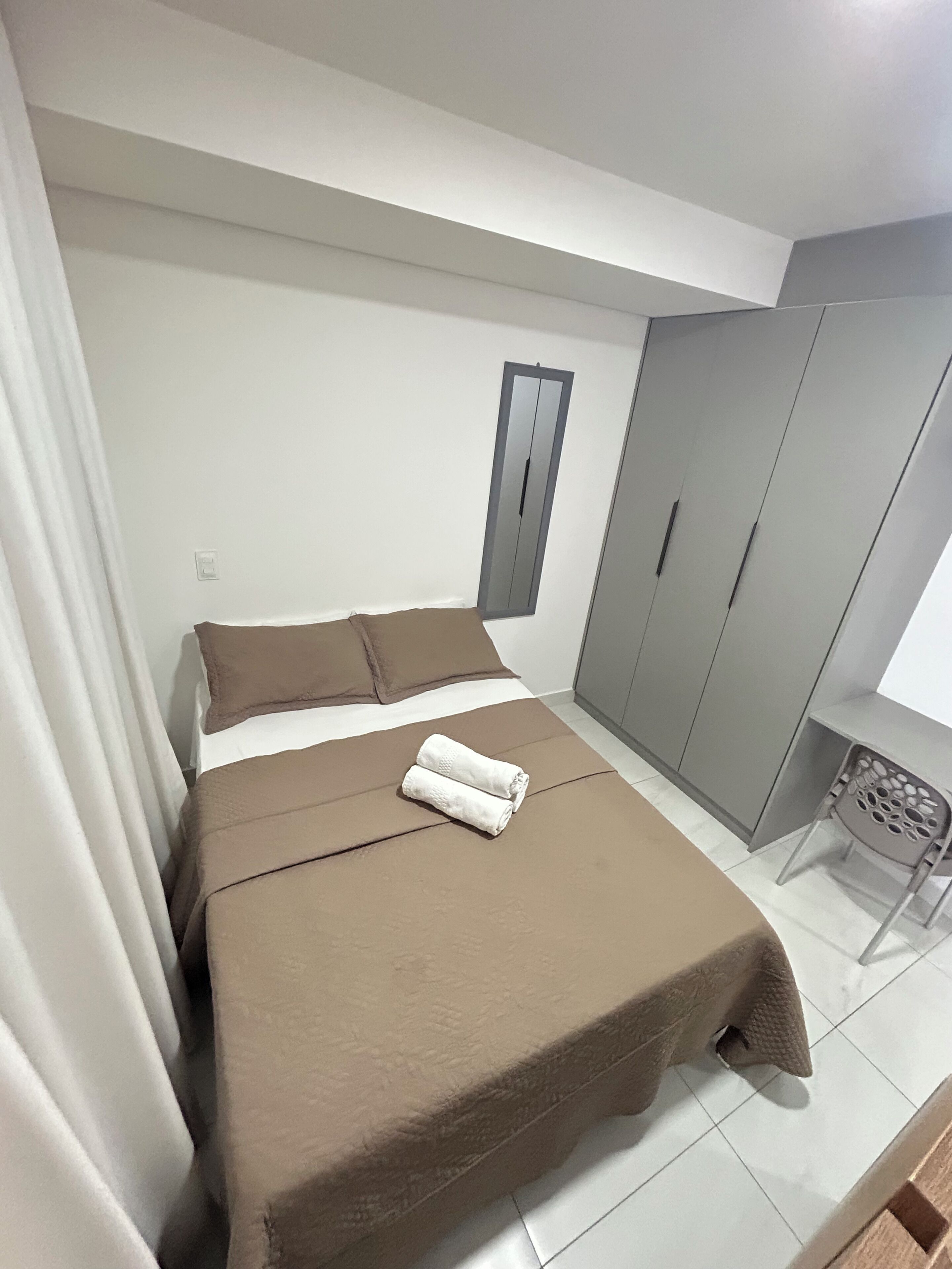 Une chambre à coucher avec un lit, une armoire et une petite table accompagnée d’une chaise.