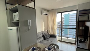 Un appartement moderne comprenant un coin repas, un canapé et une grande fenêtre donnant sur la ville.
