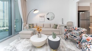A modern living room with a sofa, coffee table, and patterned chair. A mirror and a framed magazine are on the wall.
