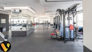 A modern gym with various exercise equipment, mirrors, and a spacious layout.
