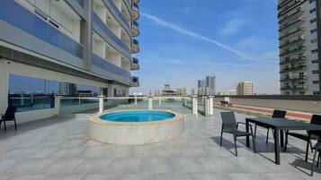 Une terrasse sur le toit avec une piscine, des sièges extérieurs et une vue sur la ville.