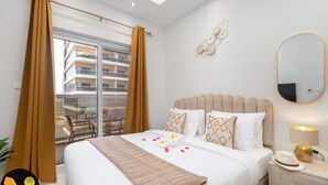 A hotel room with a bed, a nightstand, a mirror, and a view of the outside balcony.