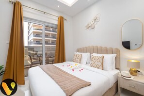 A hotel room with a bed, a nightstand, a mirror, and a view of the outside balcony.