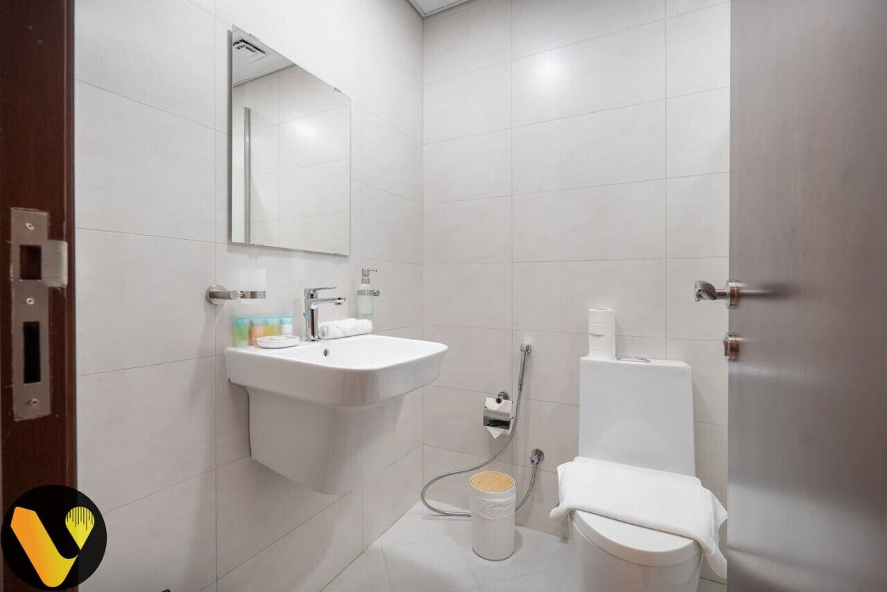 Een moderne badkamer met een wastafel, spiegel, toilet en douche.
