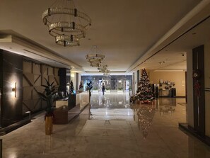 A hotel lobby with a reception desk, a Christmas tree, and a chandelier.