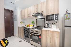 A compact kitchen with a washing machine, a stove, an oven, a microwave, and a refrigerator.
