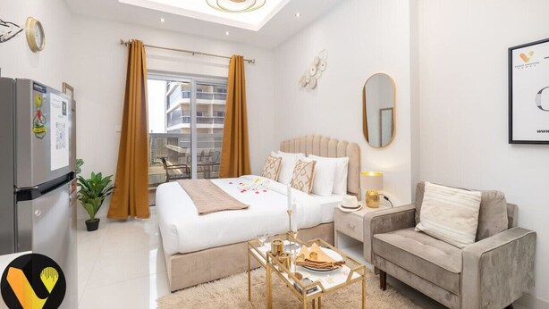 A modern hotel room with a bed, a sofa, a coffee table, a TV, and a window with curtains.