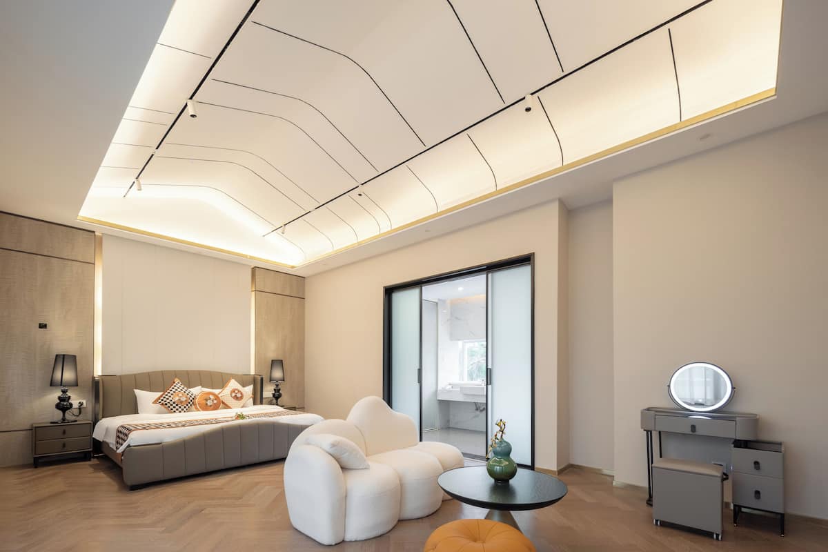 Un dormitorio moderno con una cama grande, un sofá, una mesita y un tocador con espejo.