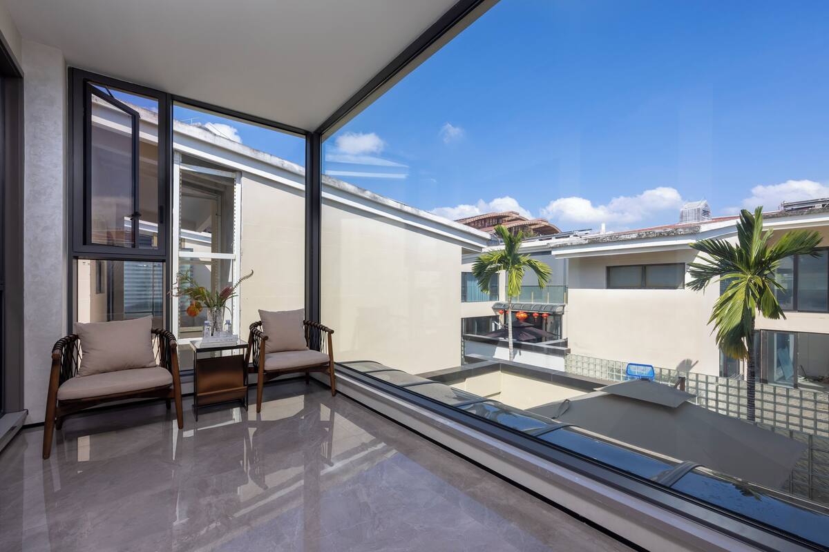 Una sala de estar moderna con balaustrada de vidrio, dos sofás, una mesa de centro y vistas a la ciudad.