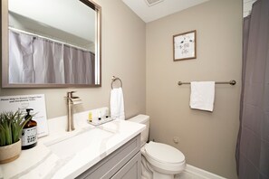 Une salle de bain avec un lavabo blanc, un miroir, des toilettes et un rideau de douche.
