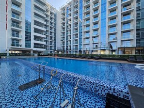 Un hotel moderno con piscina, varios balcones y un diseño arquitectónico contemporáneo.