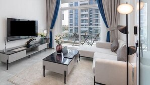 Una sala de estar moderna con televisor de pantalla plana, una mesa de centro, un sofá y un balcón con vistas a edificios.