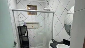 Casa de banho pequena com sanita, lavatório e espaço de duche.