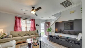 Un salon moderne comprenant un canapé, une table basse, un téléviseur et un ventilateur de plafond.