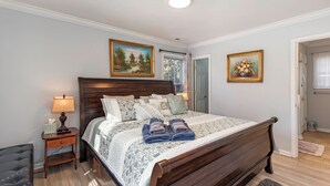 Une chambre à coucher avec un lit en bois, une table de chevet avec une lampe et deux tableaux encadrés au mur.