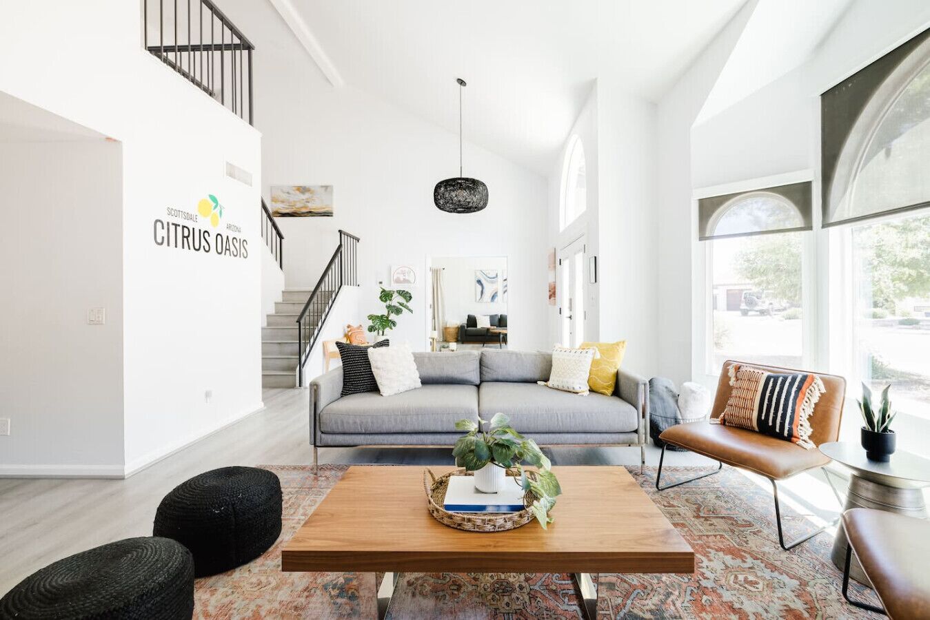 A spacious living room with a grey sofa, a wooden coffee table, and a patterned rug.