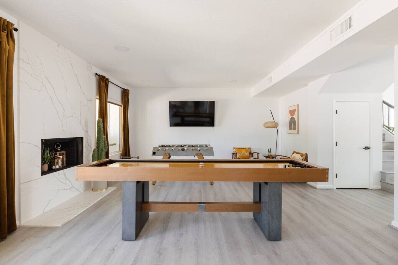 Un salon moderne avec une table de baby-foot, un téléviseur à écran plat et une cheminée.