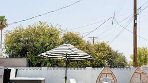 A swimming pool with white lounge chairs and a striped umbrella.