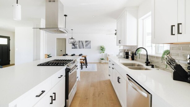 A modern kitchen with white cabinetry, a central island, and a built-in stove.