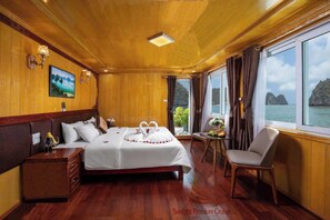 A wooden-floored bedroom with a bed, bedside table, and a view of the sea. - Halong Sunlight Premium Cruise  (Tuan Chau)