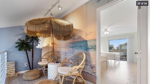 Een kamer met een strandmuur, rieten meubels en uitzicht naar buiten.