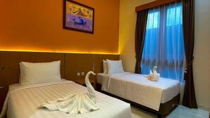 A hotel room with two beds, a mural on the wall, and a large window with curtains.