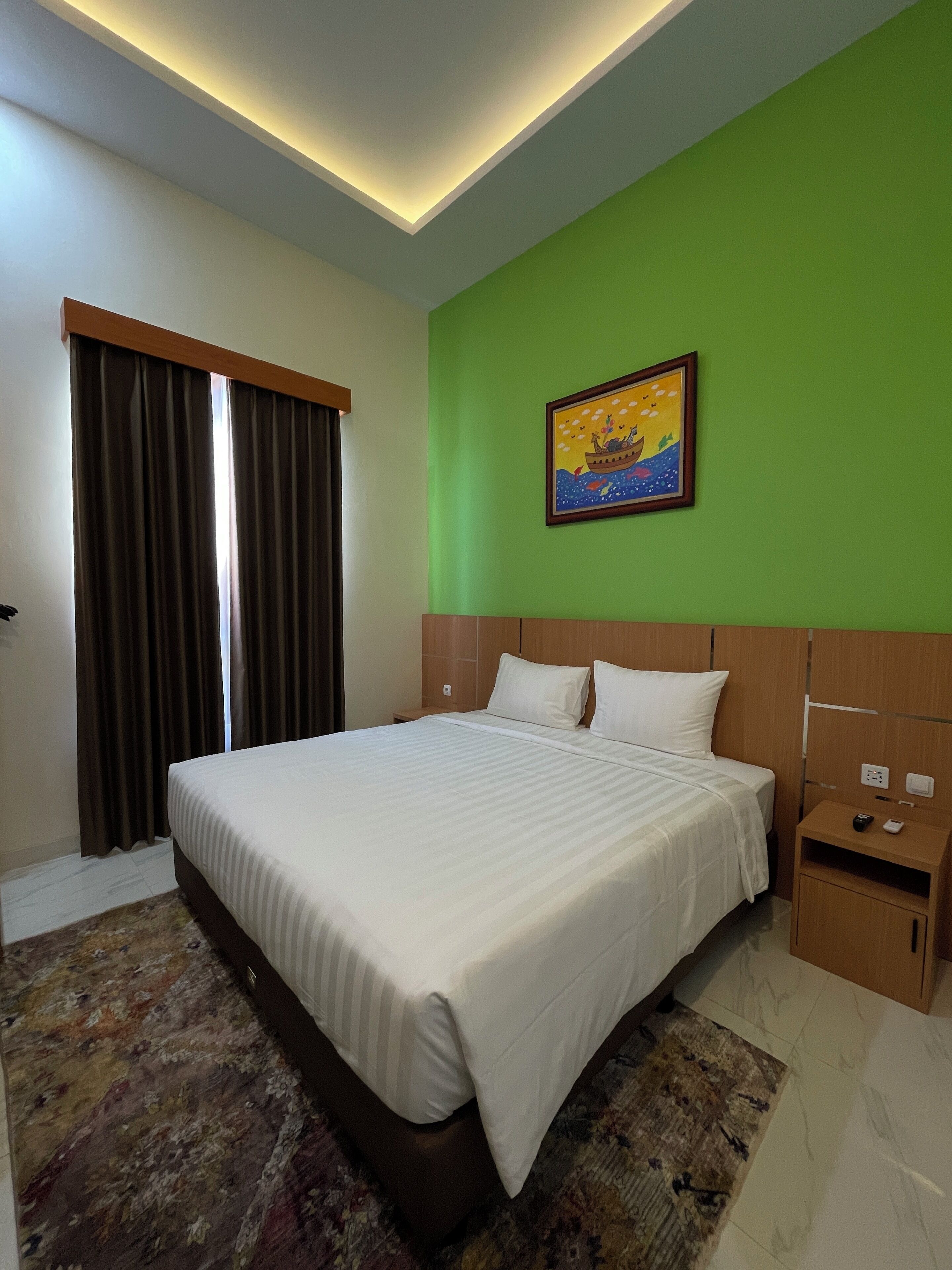 Habitación de hotel con una cama grande, una mesita de noche, un cuadro en la pared y una ventana con cortinas.