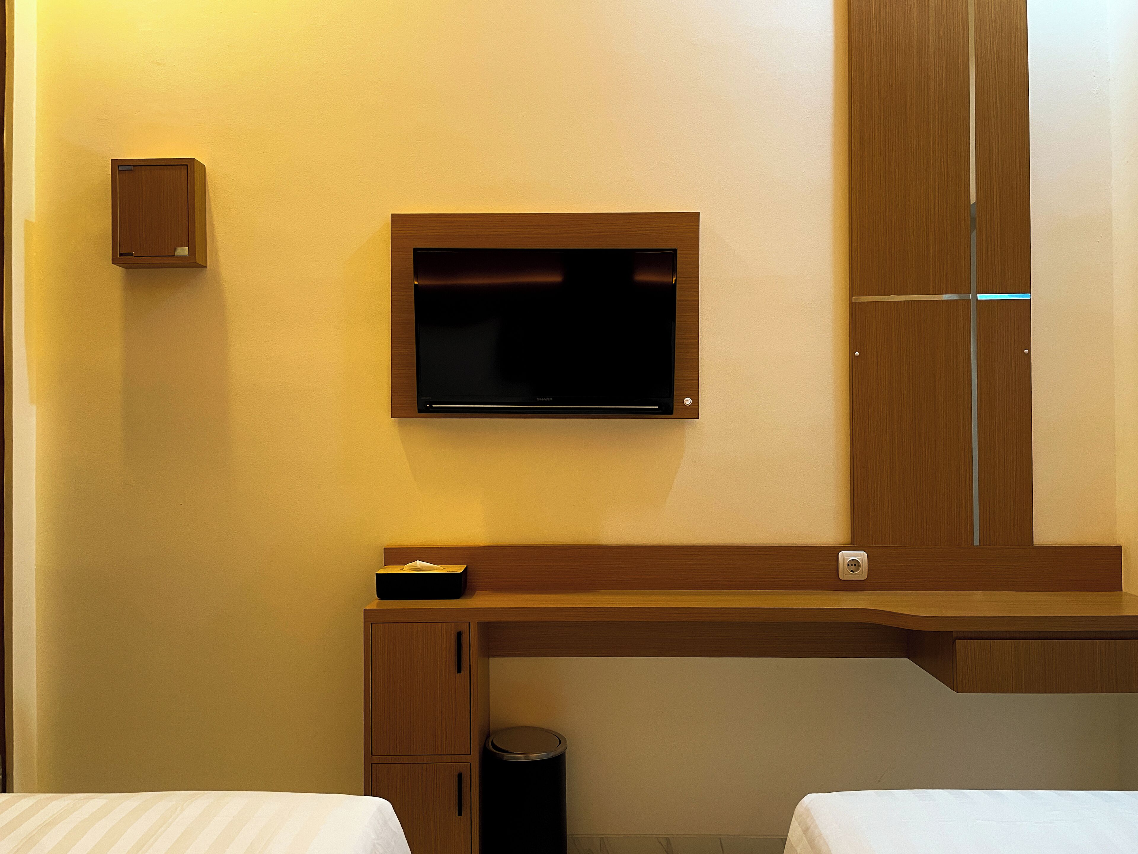A hotel room with a bed, a desk, a television, and a wardrobe.