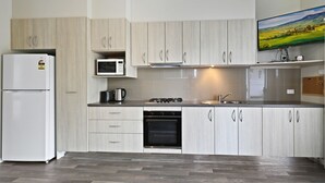 A modern kitchen with light wood cabinets, a built-in microwave, a gas stove, and a stainless steel sink. - Cabin 60 - Lake Conjola (Lake Conjola)