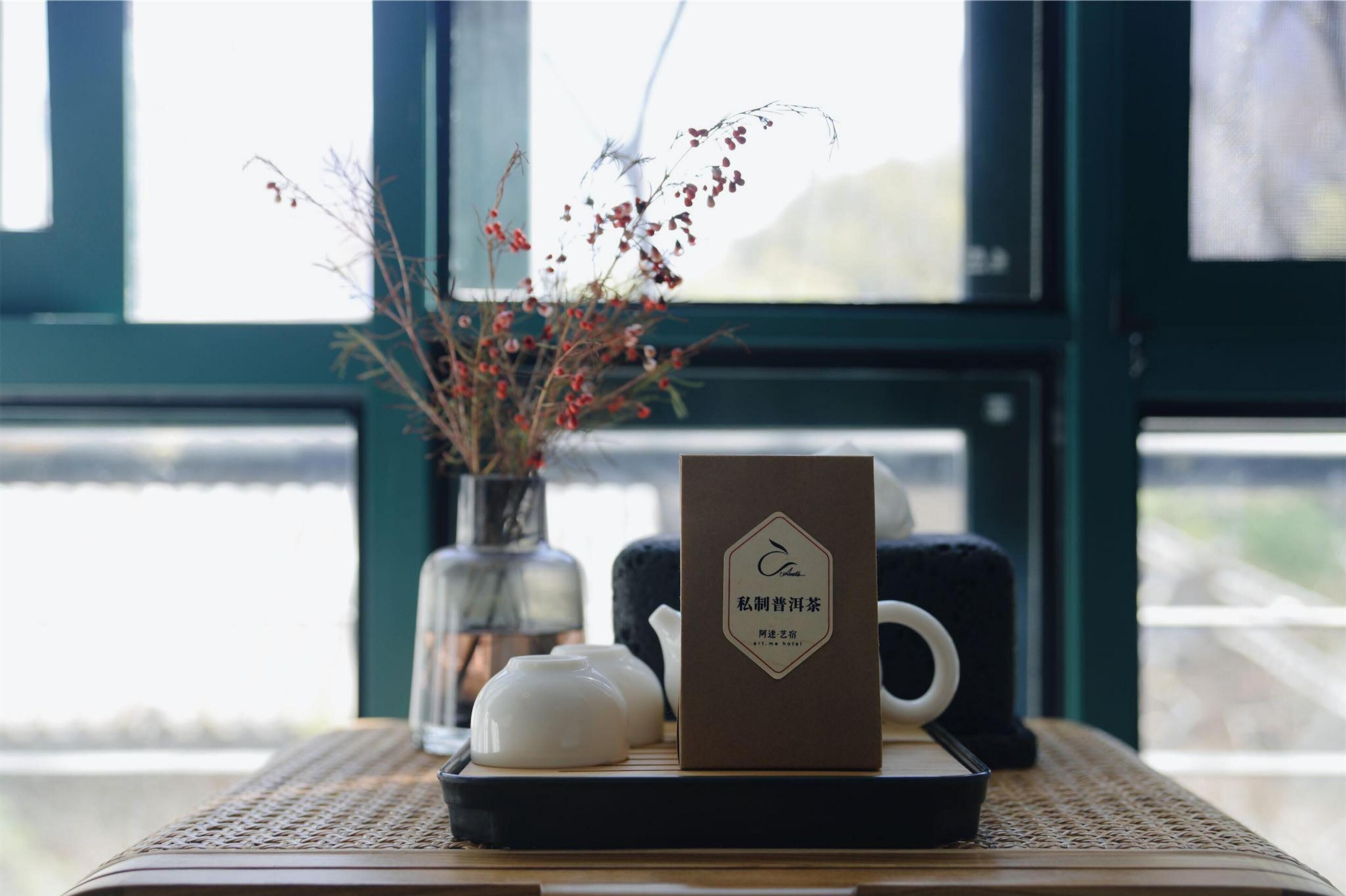 A table with a teapot, a box, and a vase with dried flowers.