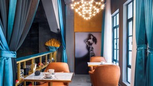 A modern interior with orange seating, a chandelier, and a mural on the wall. - AM Manye Hotel (Kunming)