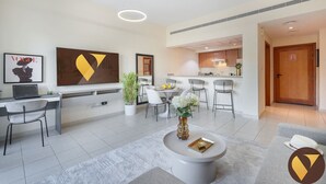 Un hall d’hôtel moderne avec un comptoir d’accueil, un espace salon et une cuisine visible à travers une porte ouverte.