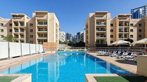 Une piscine entourée de bâtiments à plusieurs étages, avec des chaises longues à proximité.