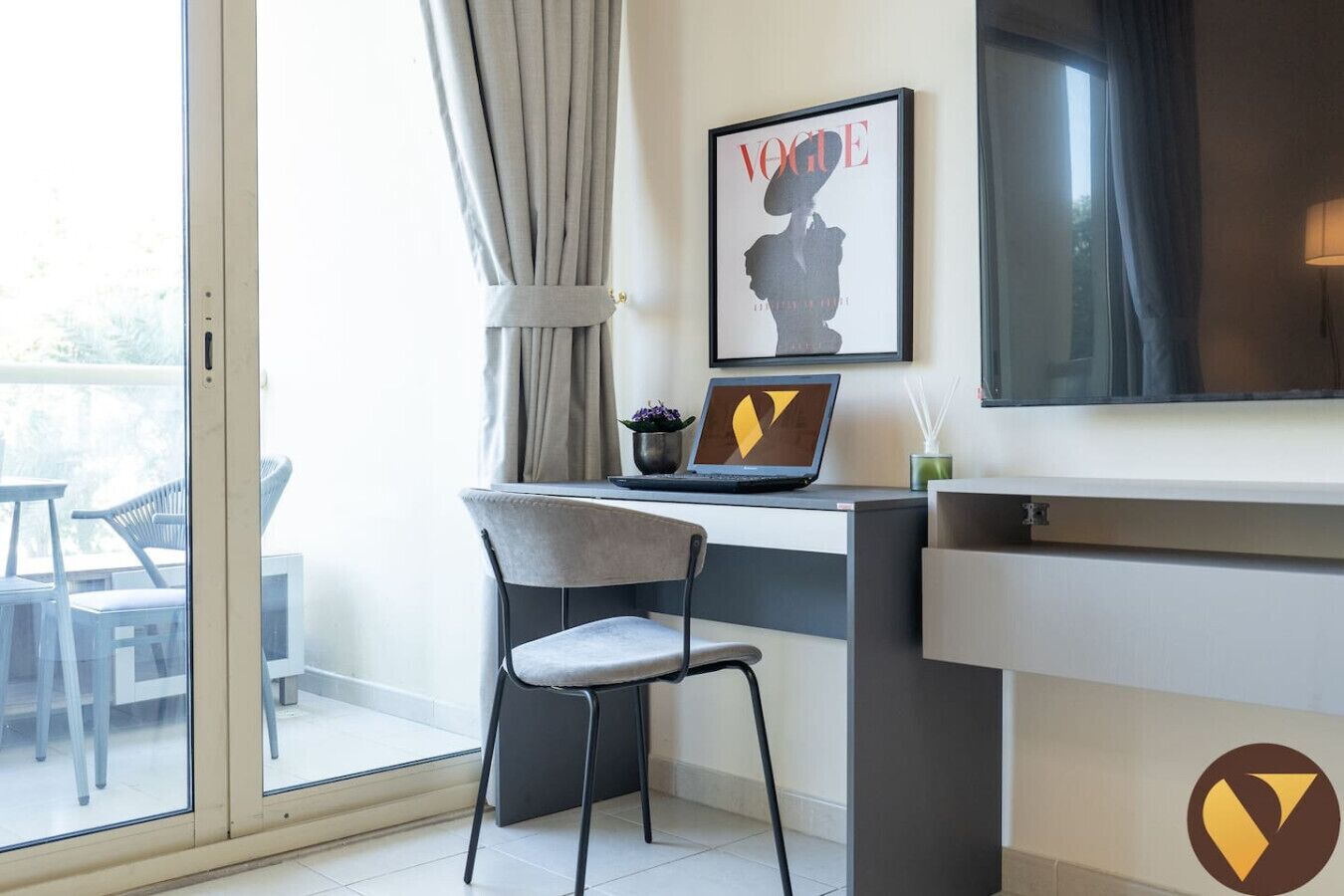 Een moderne hotelkamer met een bureau, laptop en een tijdschrift in een lijst aan de muur.