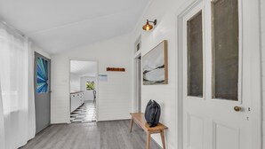 Un couloir avec un banc en bois, un porte-manteau et une porte dotée d’une fenêtre.
