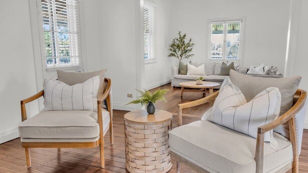 Un salon spacieux doté d’un plancher en bois, de deux fauteuils, d’un canapé et d’une table basse.