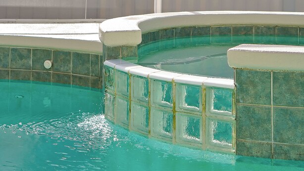 Una piscina con borda piastrellata e bordo bianco.