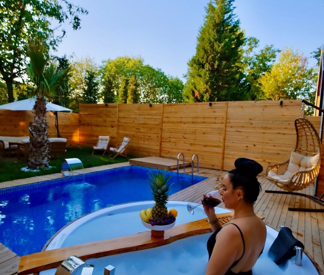 A swimming pool with a hot tub, surrounded by wooden deck and lounge chairs.