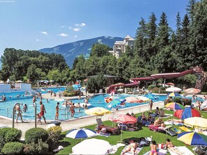 A resort with multiple swimming pools, a water slide, and sunbathing areas.